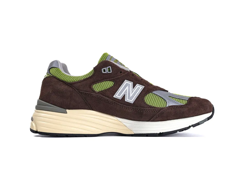 Brown suede sneaker with green mesh accents and grey details on the sole.