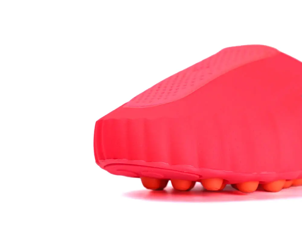 Red rubber shoe sole with orange traction pods, close-up view.
