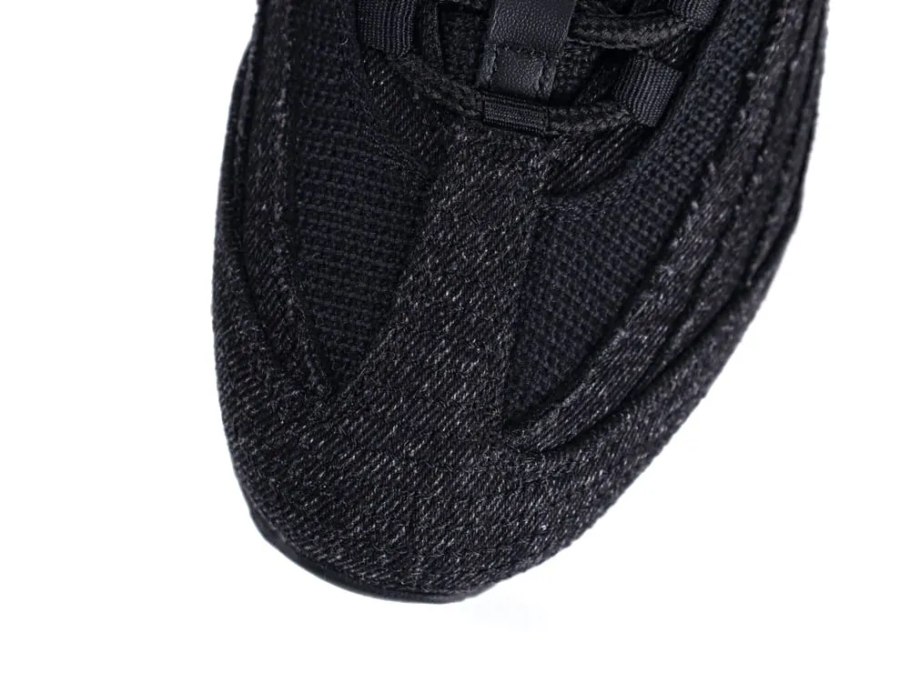 Close-up of sneaker toe made of black woven fabric with textured detail.