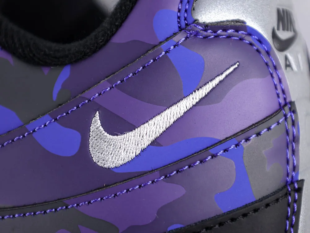 Close-up of purple and blue camouflage shoe with embroidered silver logo.