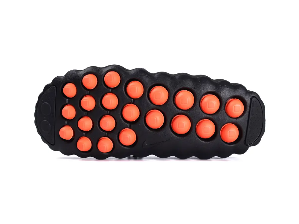 Black and orange rubber shoe sole with circular traction knobs.