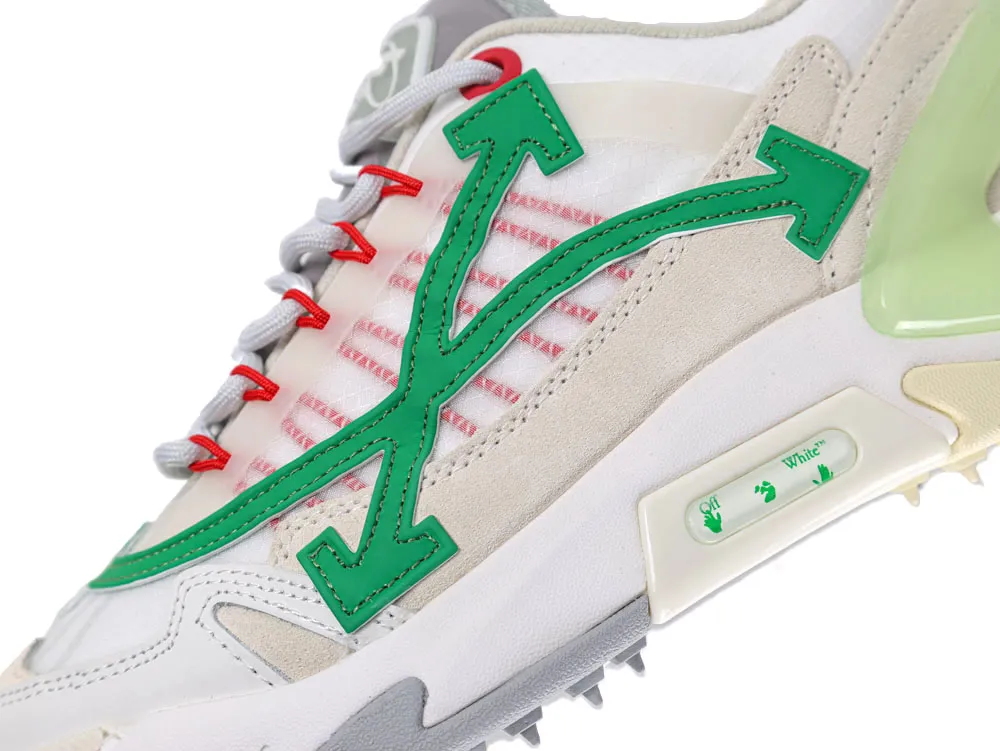Close-up of sneaker with green arrow design, red laces, and mixed materials.