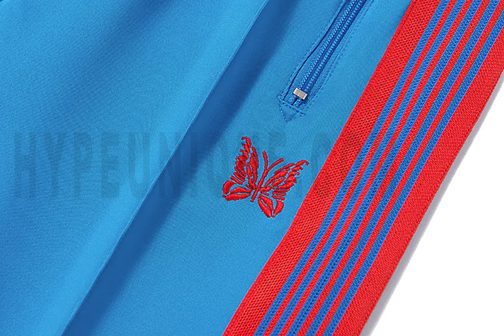 Close-up detail of the track pants pocket and delicate butterfly embroidery.