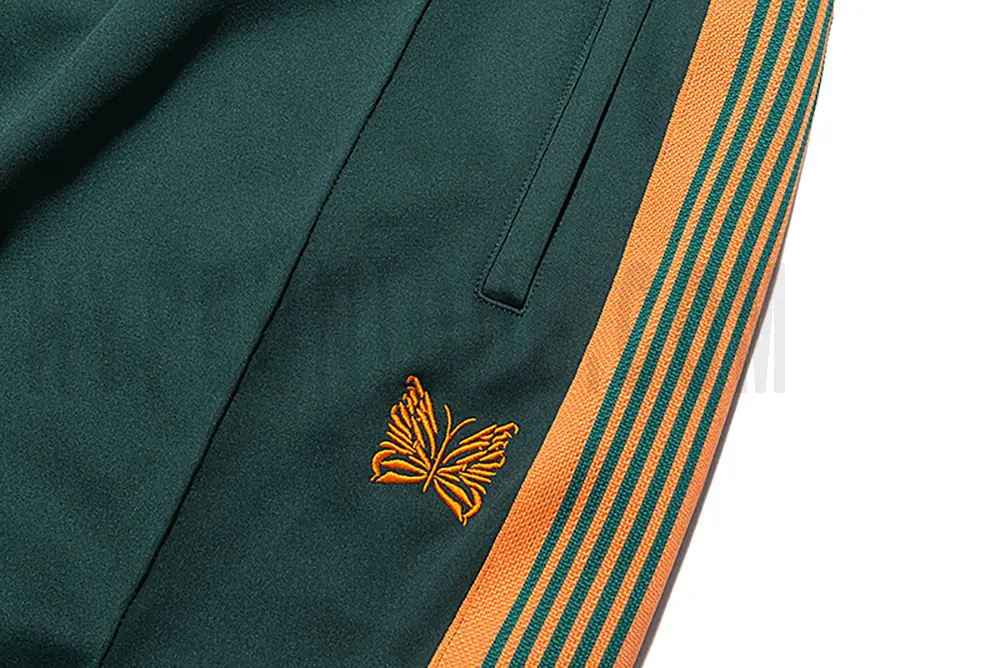 Close-up detail of the track pants pocket and delicate butterfly embroidery.