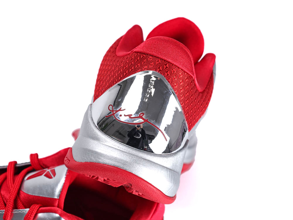 Red mesh and silver metallic heel of a sneaker with signature detail.