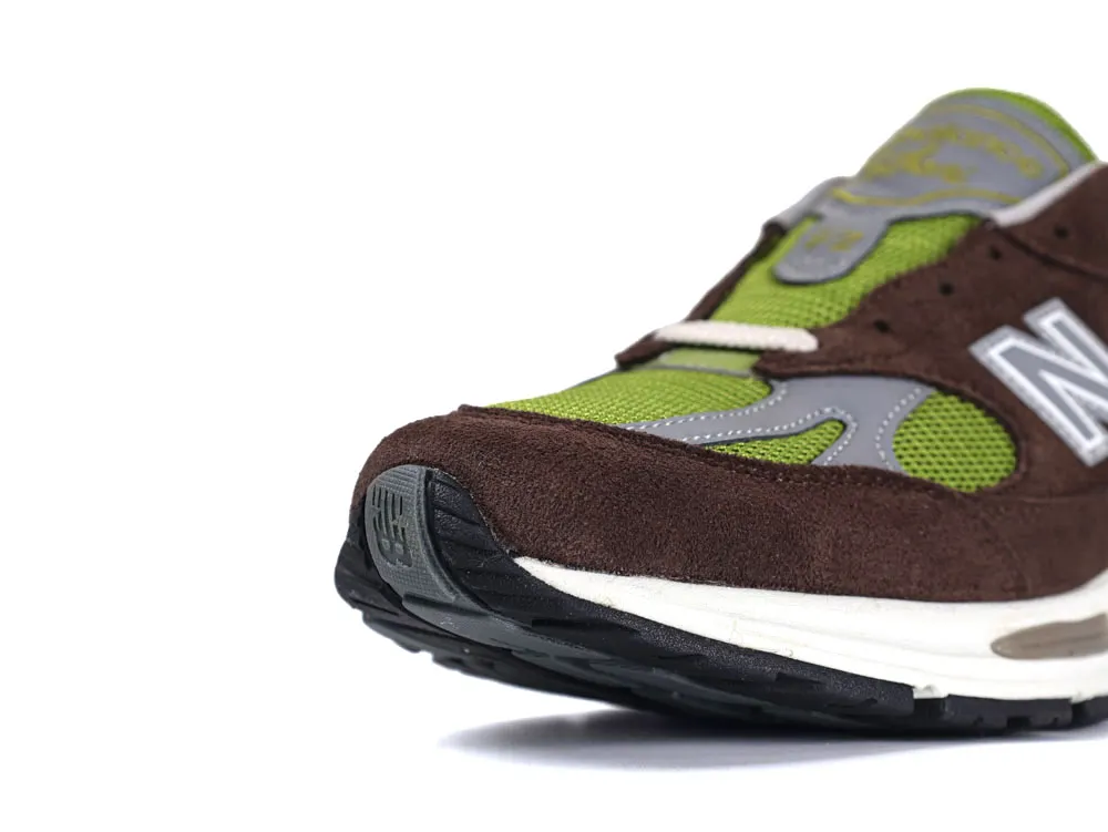 Brown and green suede sneaker with mesh, featuring a rubber sole and logo detail.