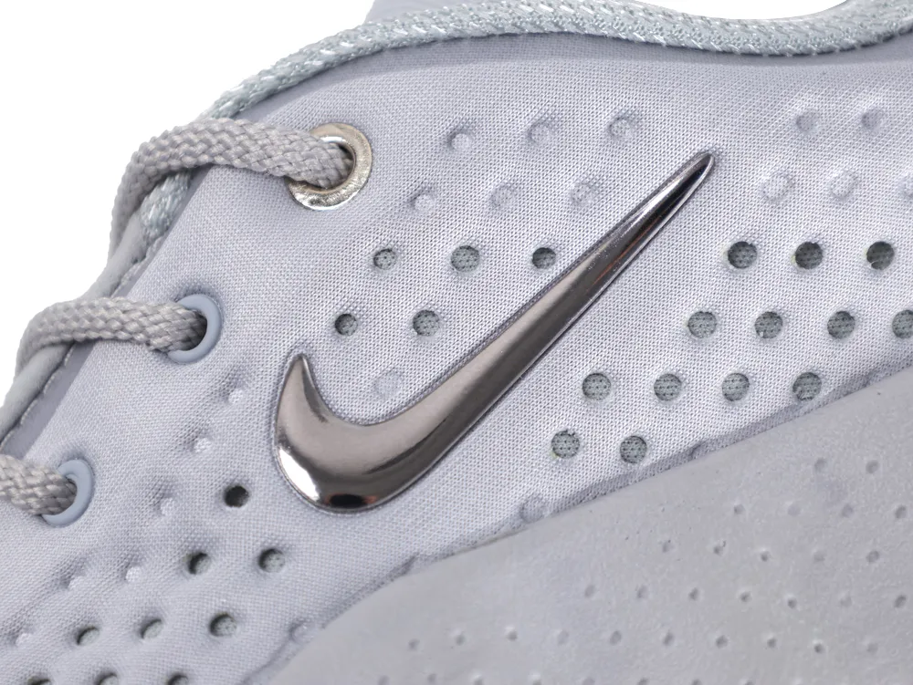Close-up of a gray textile shoe with metallic logo and perforated design.