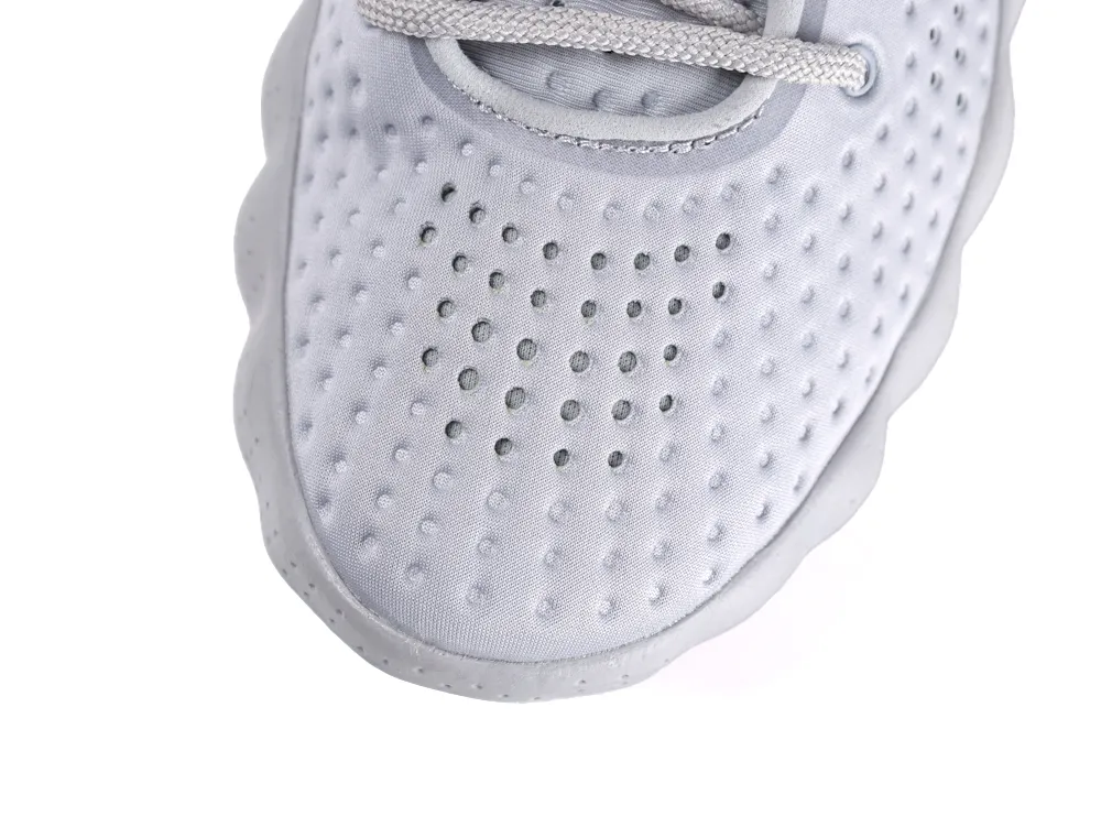Close-up of a gray perforated fabric shoe toe with textured sole and laces.