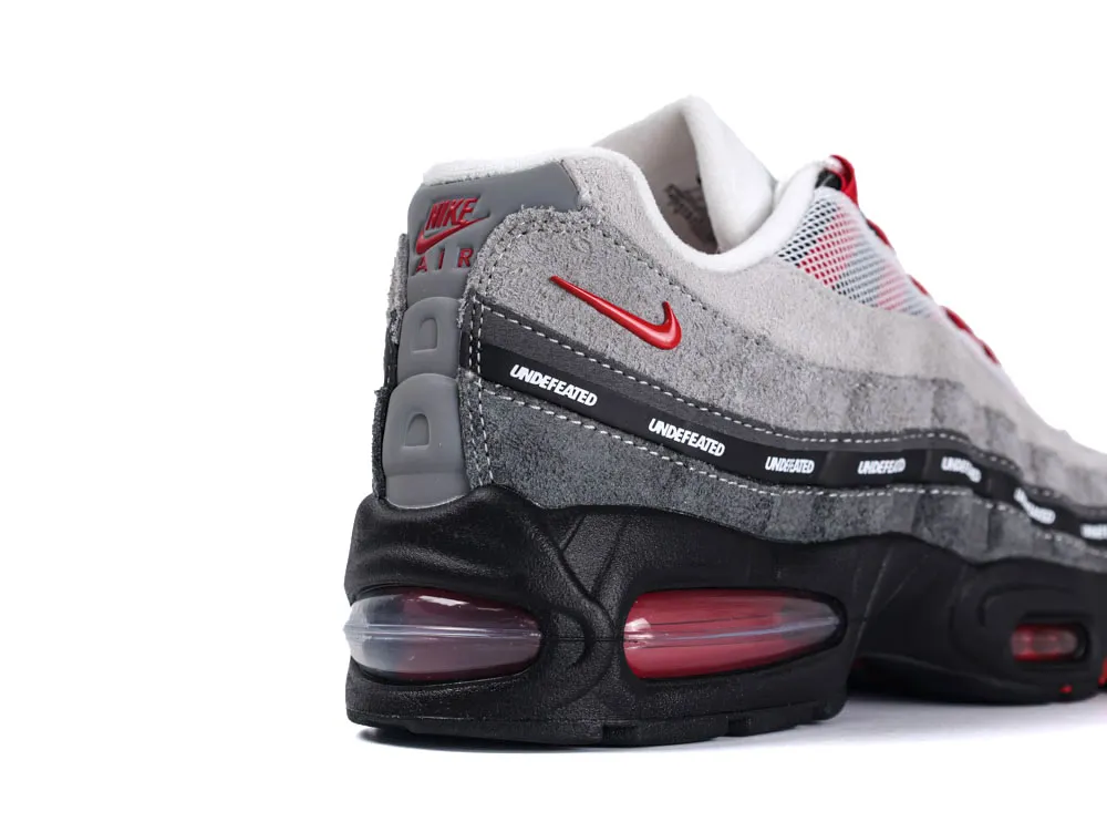 Gray suede sneaker with black sole, red accents, and branded details.