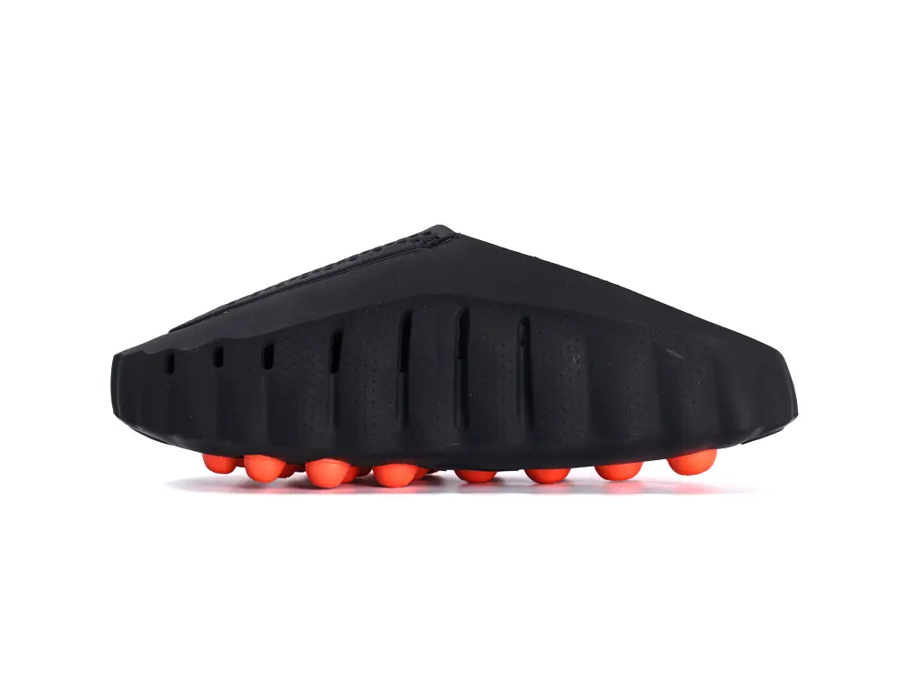 Black shoe with a ridged rubber sole and bright orange round accents.