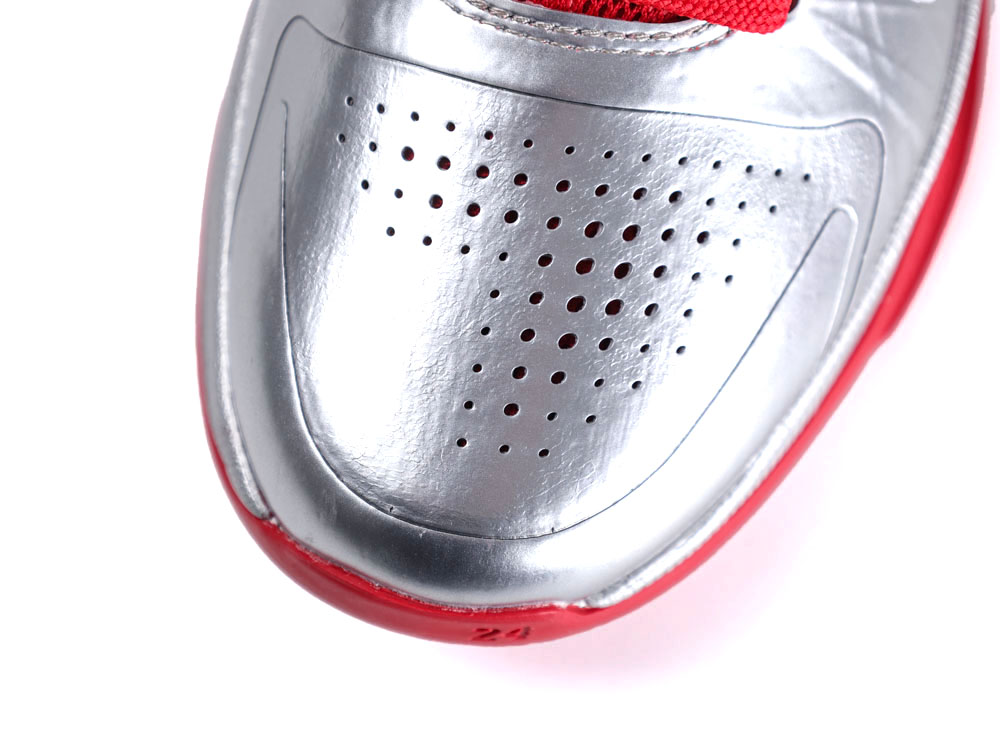 Silver leather shoe toe with perforations and red accents.