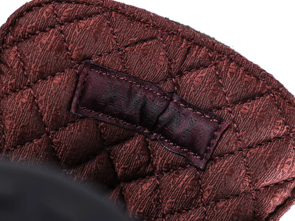Quilted maroon fabric with intricate stitching and a dark sewn-in label patch.