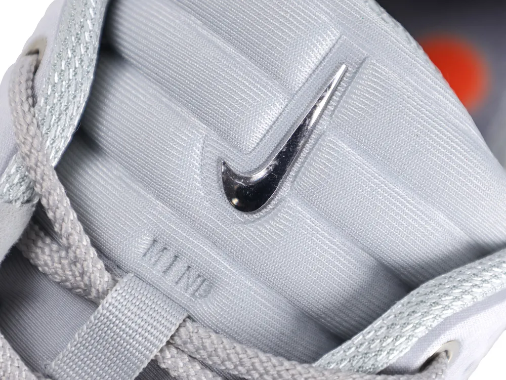 Close-up of a gray fabric sneaker tongue with a shiny metal logo detail.