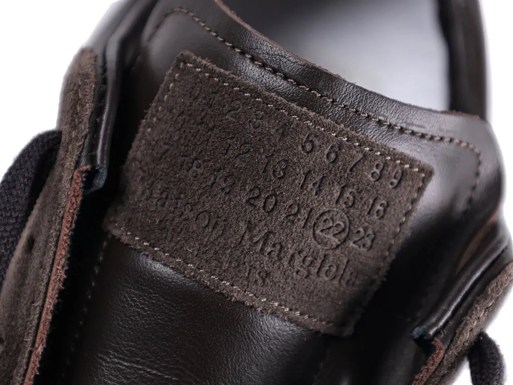 Close-up of a dark brown leather shoe with textured suede detailing and stitching.