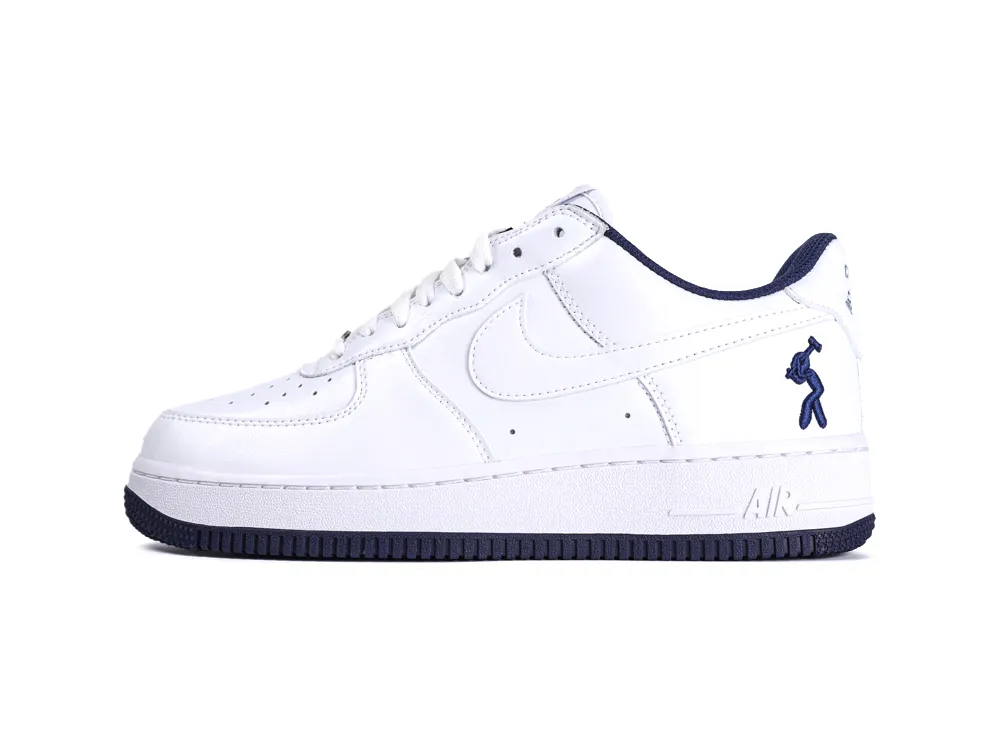 White leather sneaker with navy blue accents and rubber sole.