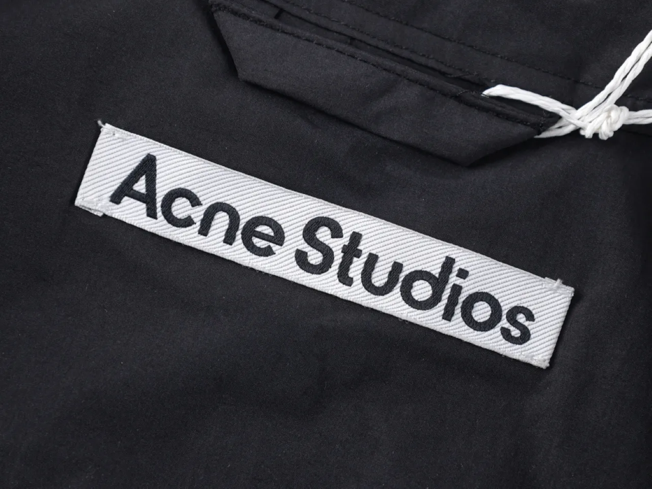 Label on black textile garment with printed logo.