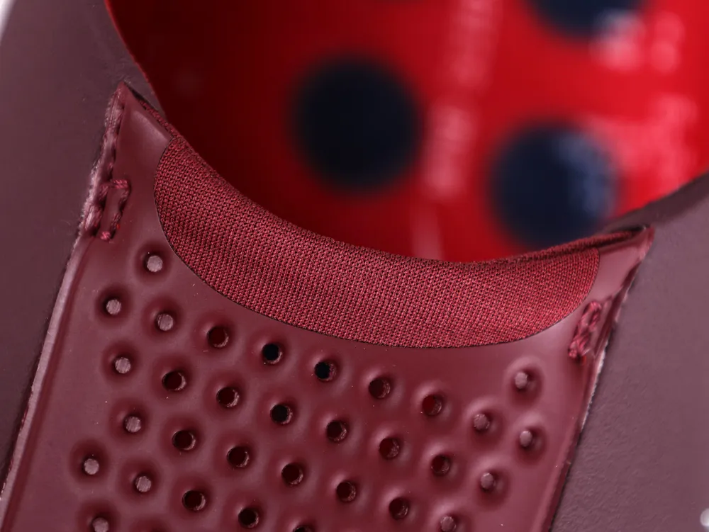 Top-down view into the elastic burgundy ankle collar and the perforated inner lining of the slip-on shoe.
