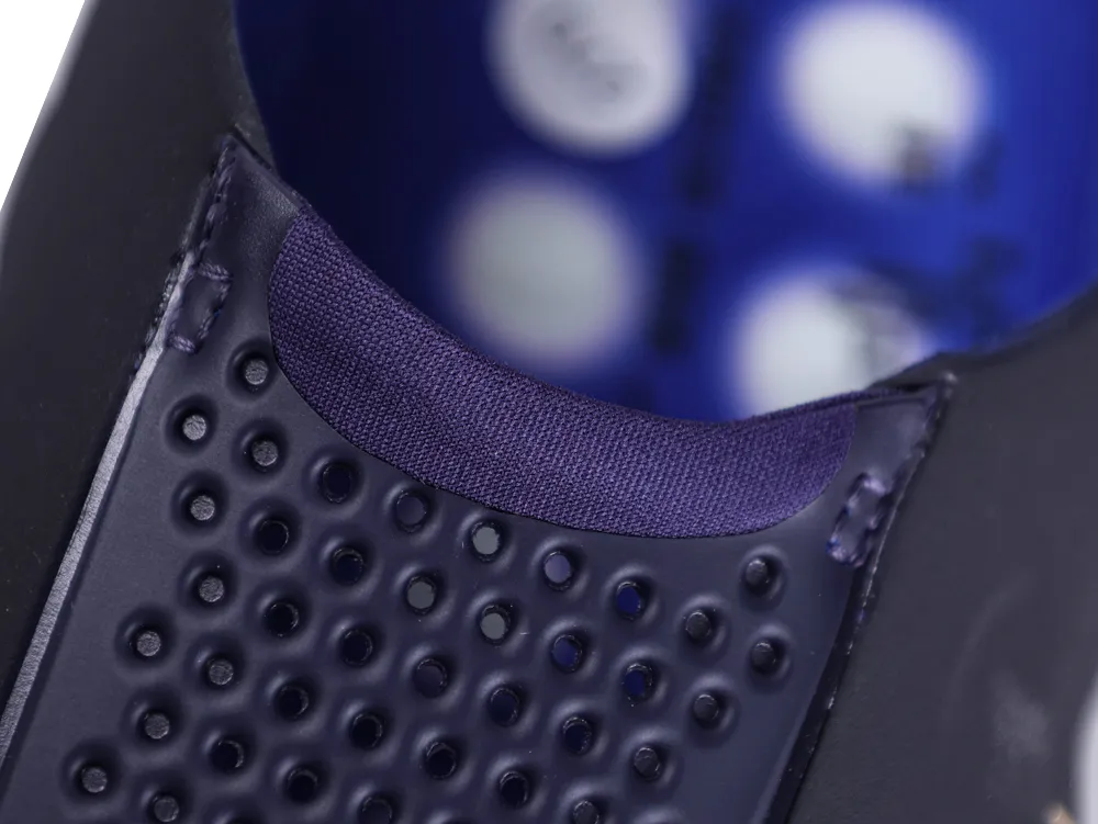 Close-up of the elasticated navy blue collar and the perforated upper of the slip-on shoe.