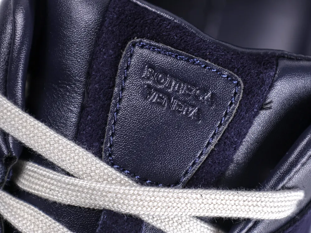 Close-up of navy leather sneaker with textured design and white laces.