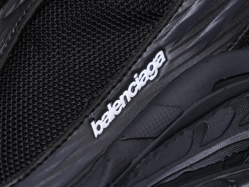 Close-up of a black mesh sneaker with embossed plastic detailing and brand logo.
