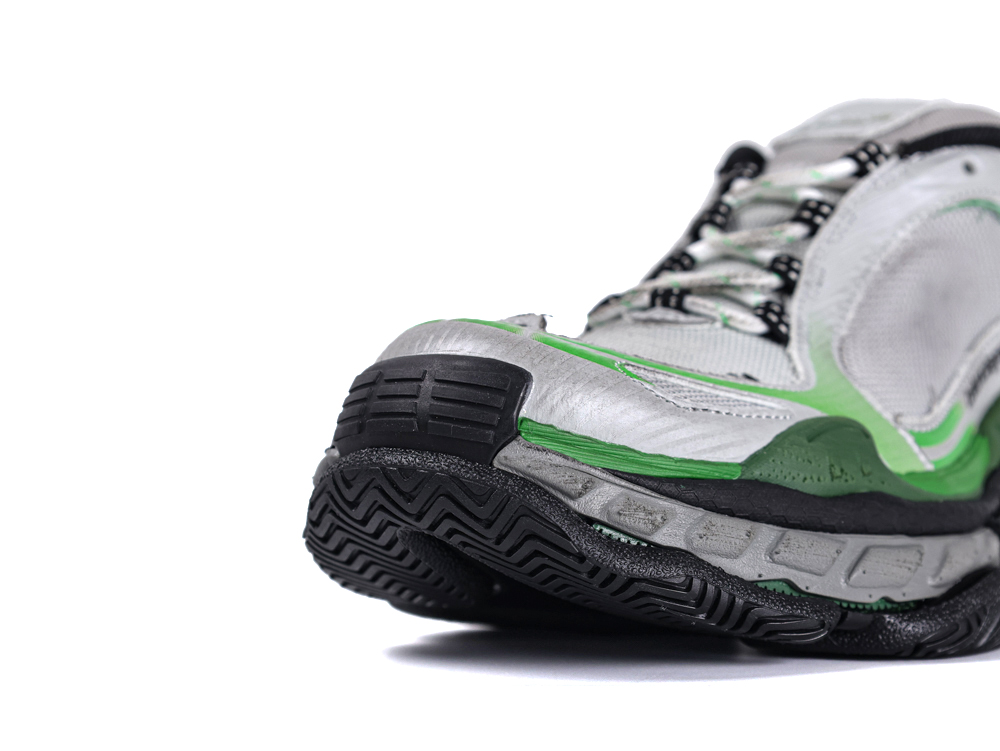 Close-up of a gray and green sneaker with black sole and mesh material.