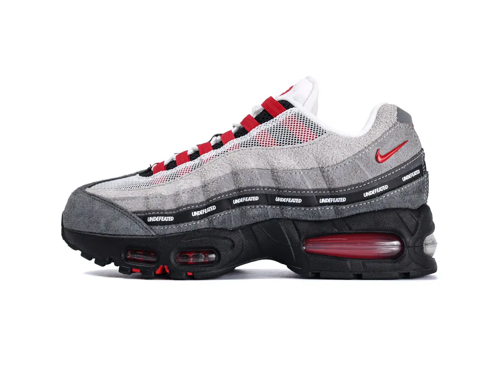 Gray and black sneaker with suede and mesh material, featuring red accents and branding.