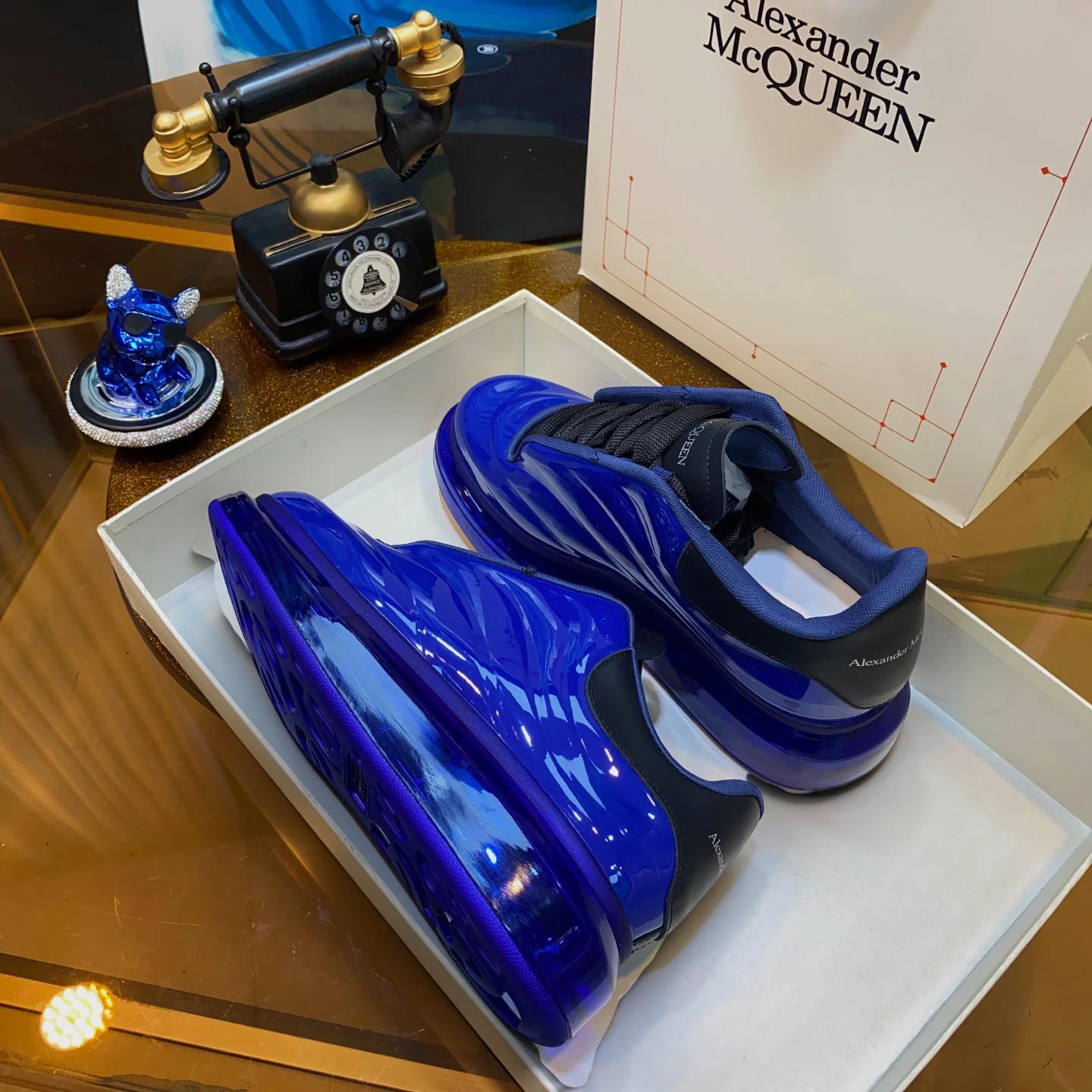 Blue patent leather sneakers with black accents in a white box.