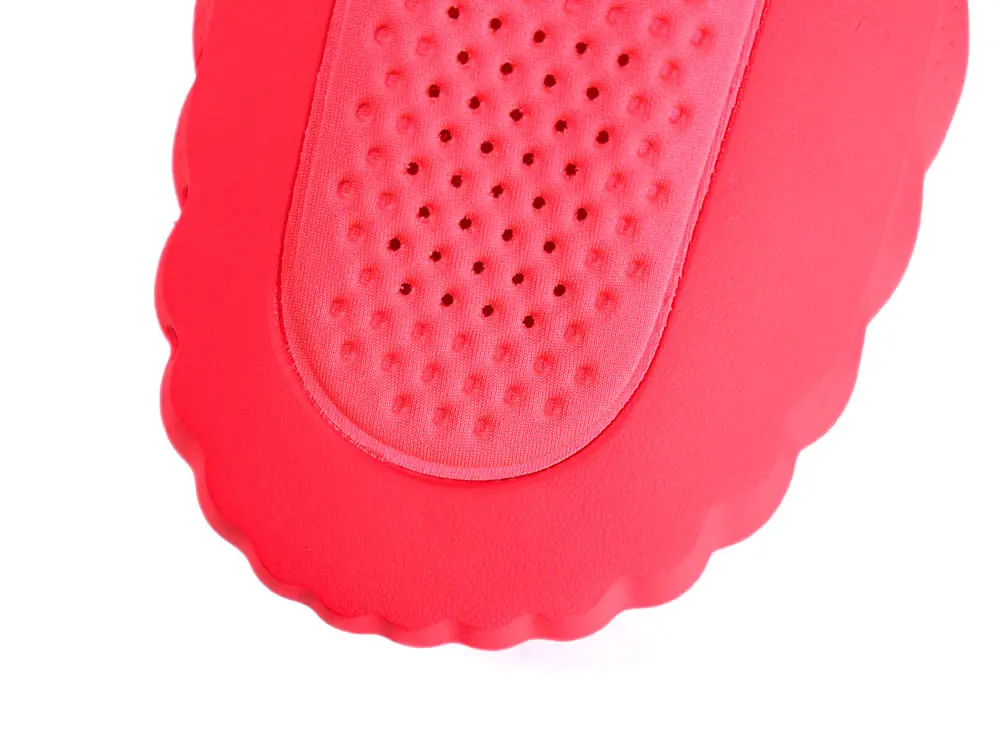 Red rubber shoe sole with textured grip and perforated cushioning.