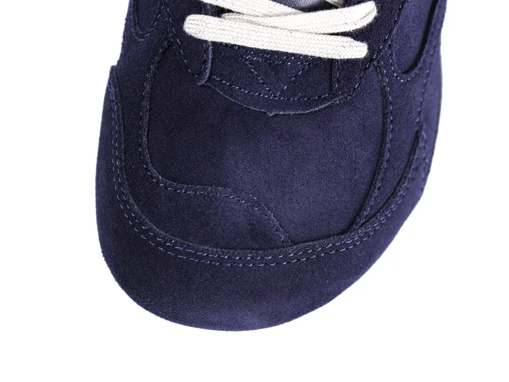 Close-up of dark blue suede sneaker toe with white laces.