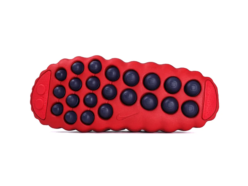 Full view of the bright red rubber outsole with numerous dark navy blue circular traction pods.