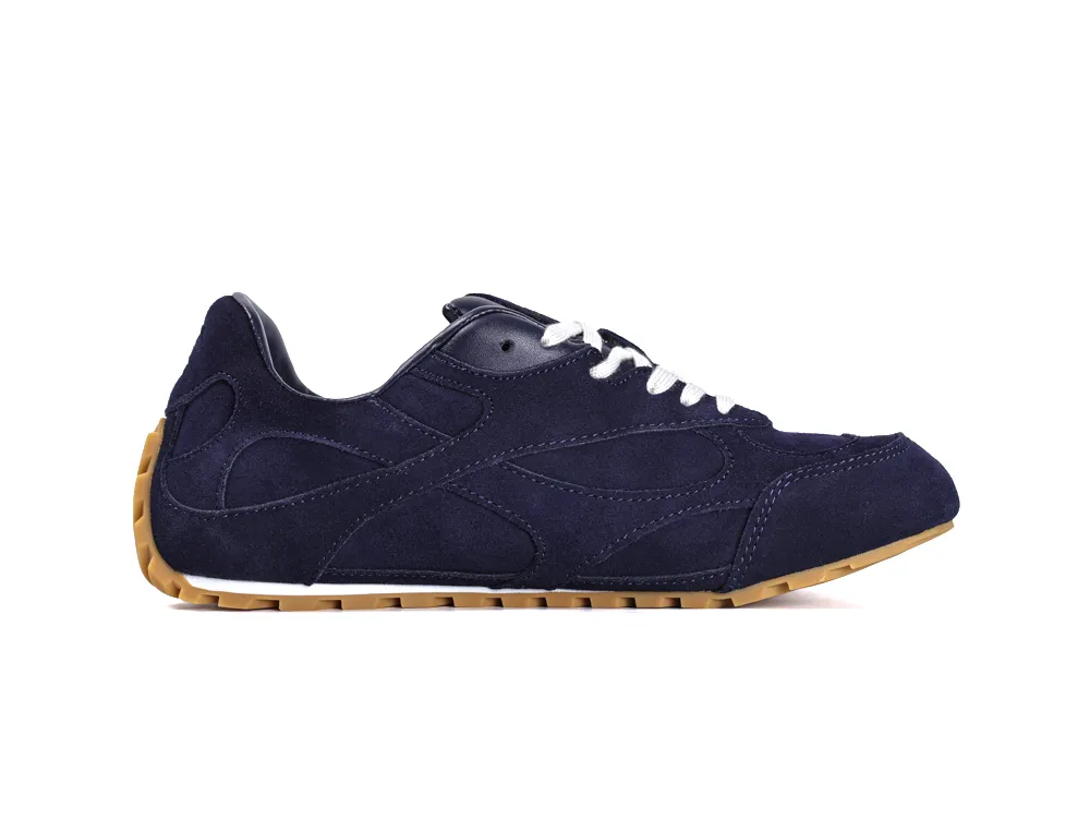 Navy blue suede sneaker with white laces and tan rubber sole.