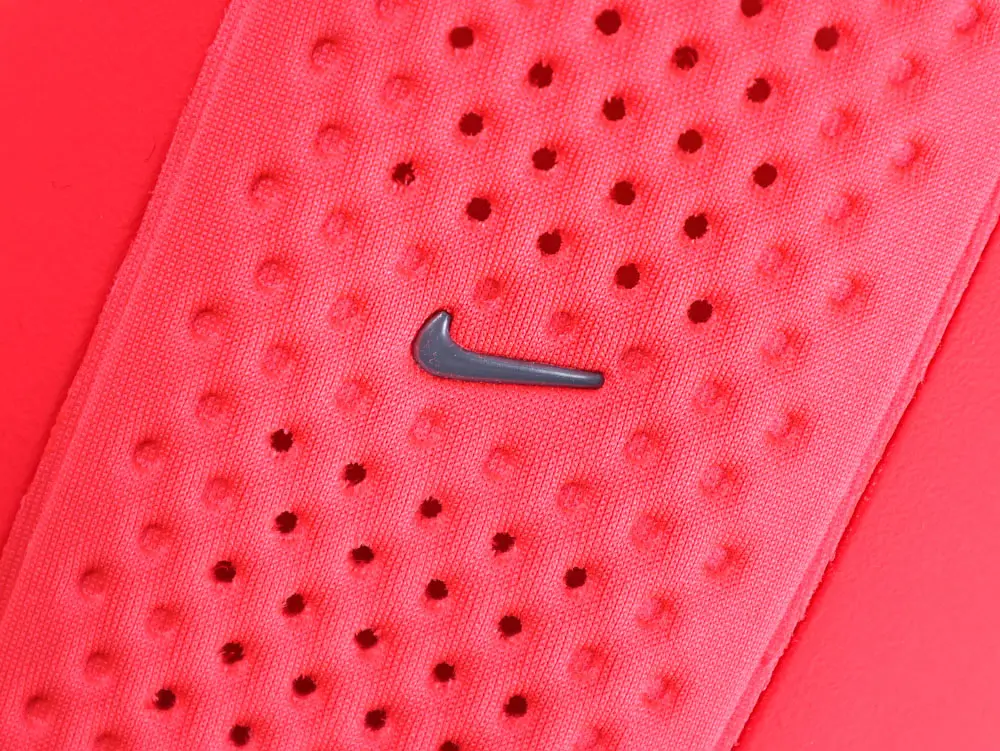 Red perforated fabric material with a small, black logo in the center.