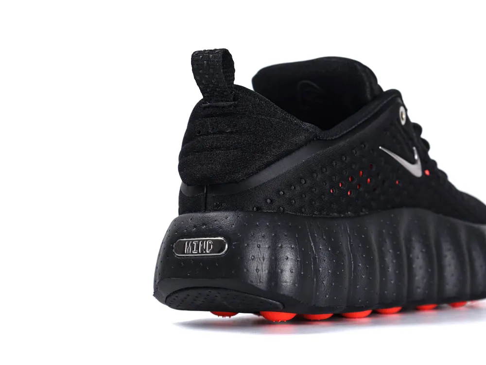 Black textile sneaker with rubber sole and red accents, featuring metallic branding.