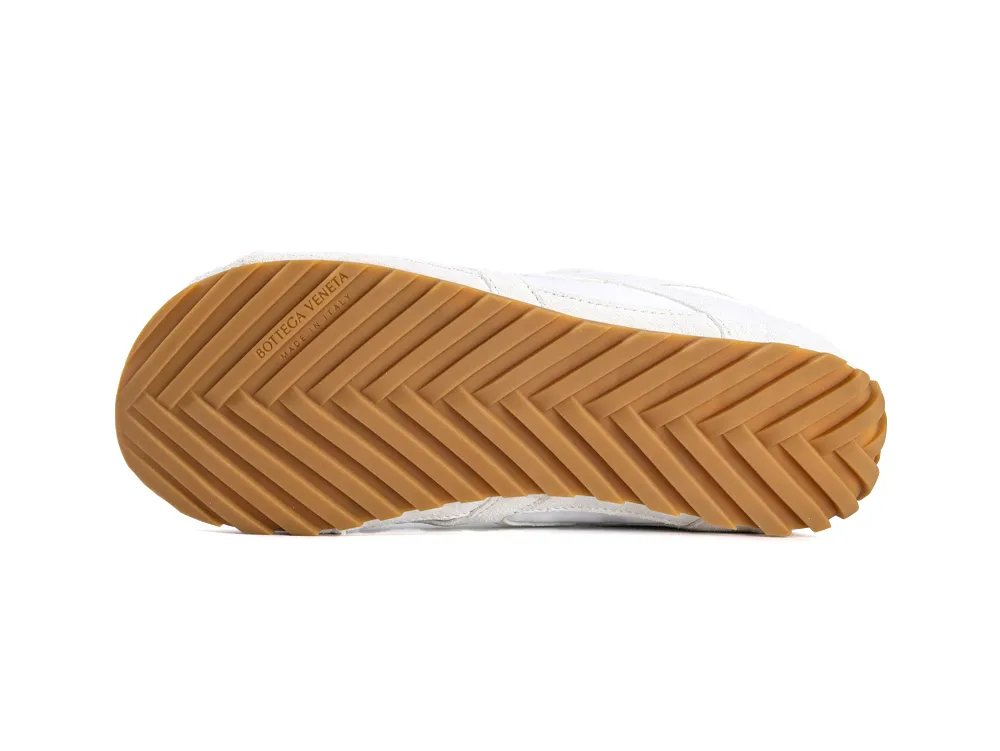 Brown gum sole of a sneaker with a herringbone pattern for traction.