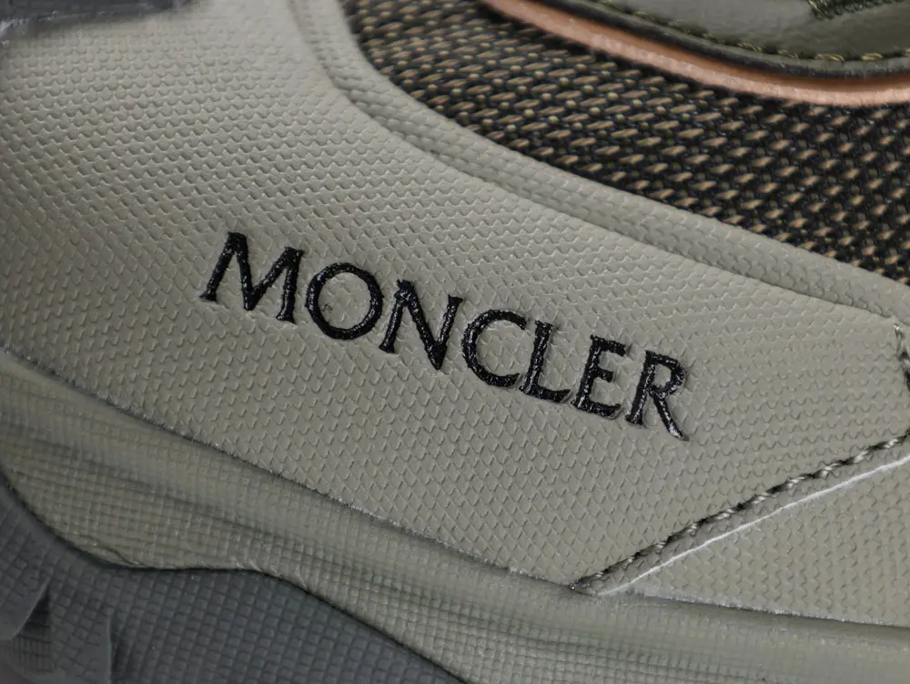 Close-up of a Moncler shoe, showcasing textured gray fabric, black mesh, smooth stitching, and subtle angles with contrasting tones.