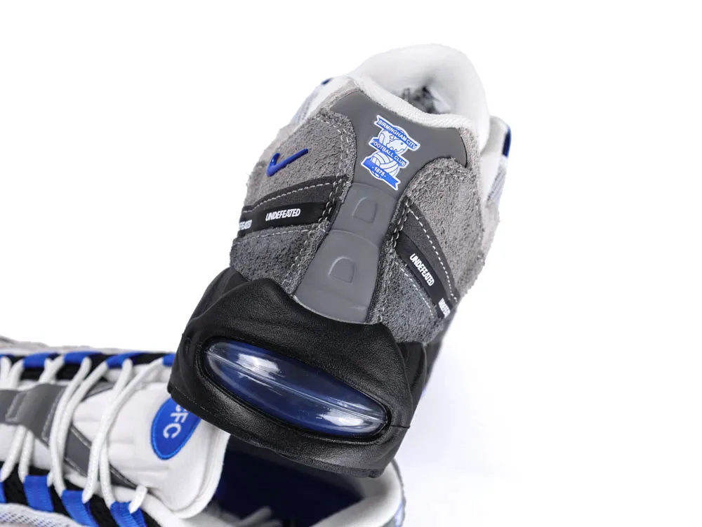 Gray and blue sneaker with suede and leather materials, featuring a visible air cushion.