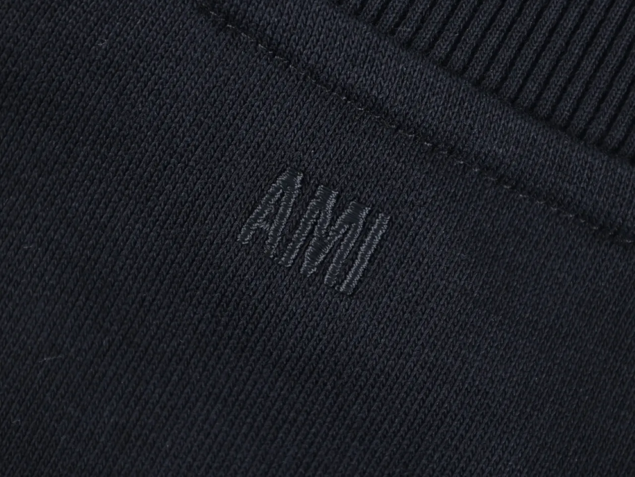 Embroidered letters "AMI" design detail.
