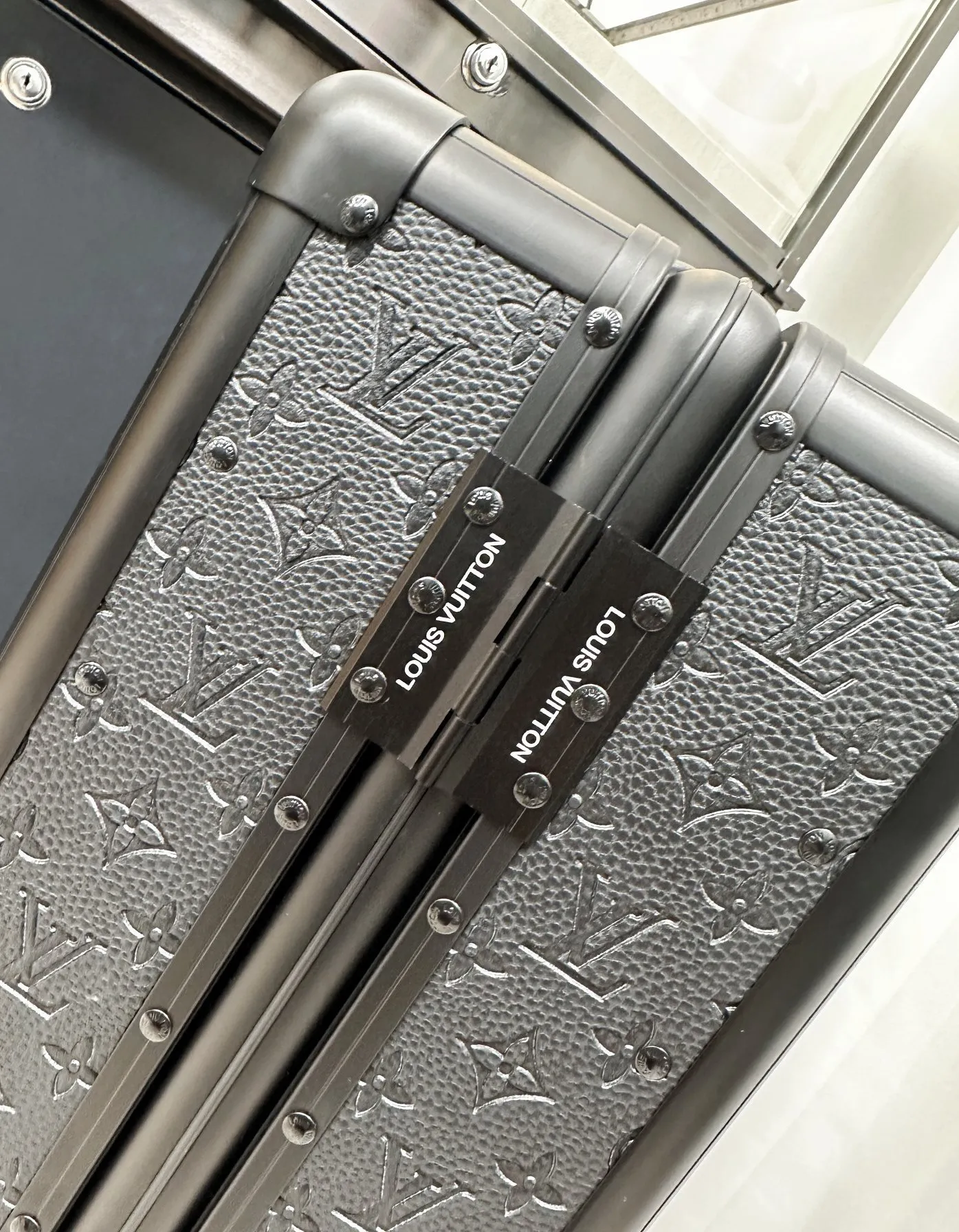 Black embossed monogram rolling luggage frame detail