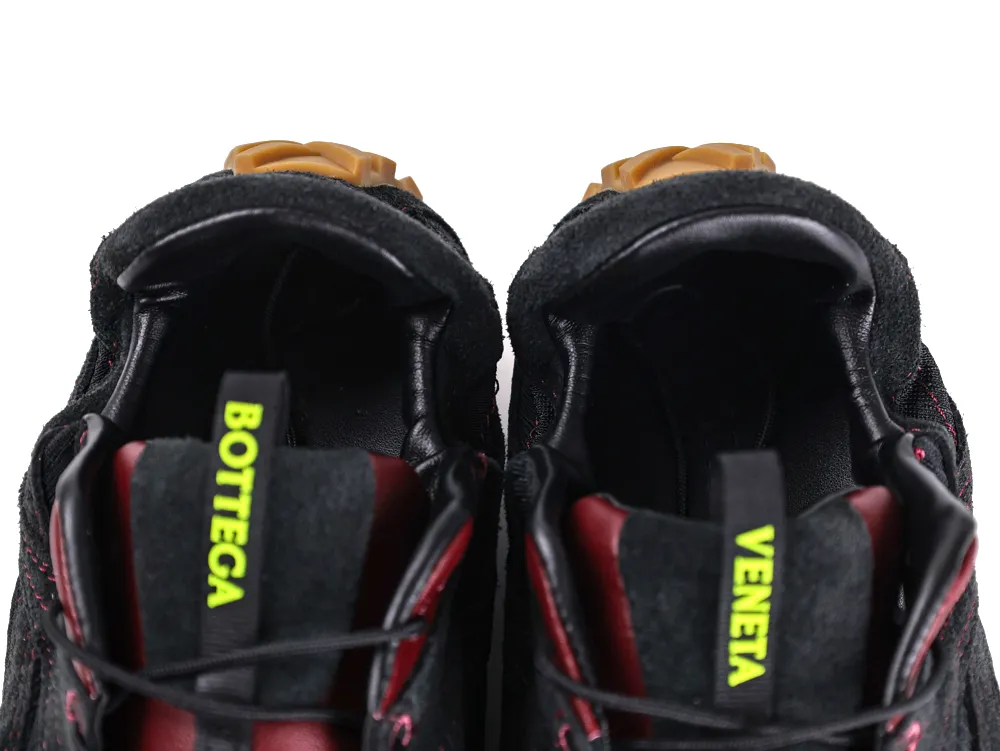 Black fabric sneakers with red leather interior and neon green branded tags.