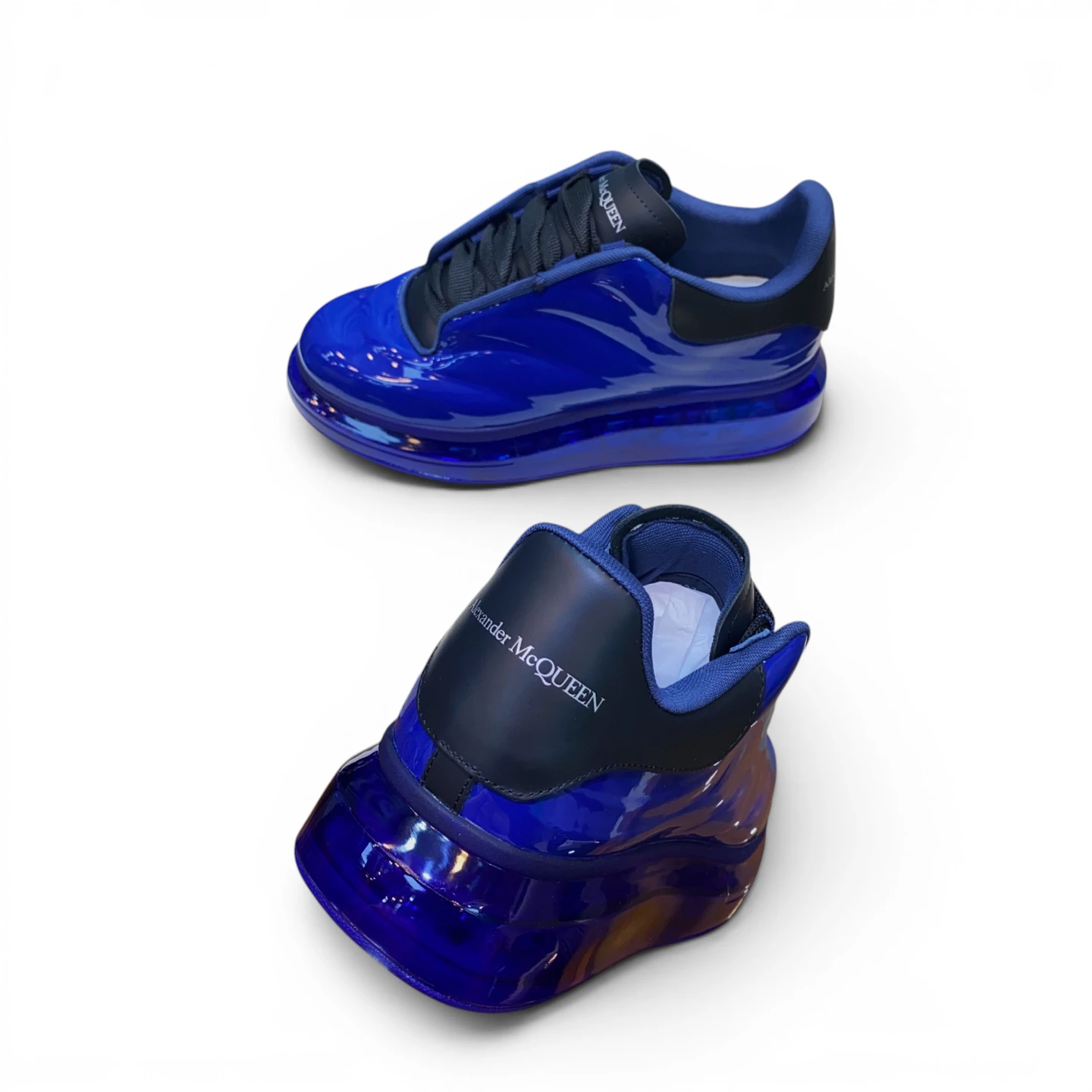Blue glossy sneakers with black accents and rubber soles, featuring branding on the heel.