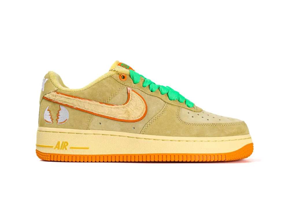 Tan suede sneaker with orange and green accents, plush details, and rubber sole.