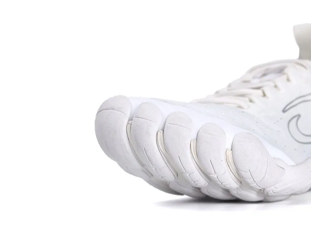 White sneaker with a textured fabric upper and a unique gripped sole design.