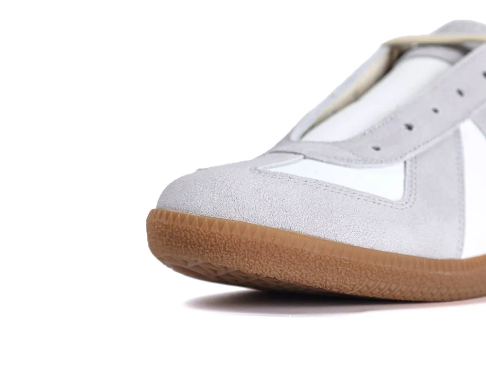 Close-up of gray suede sneaker with a white panel and gum rubber sole.