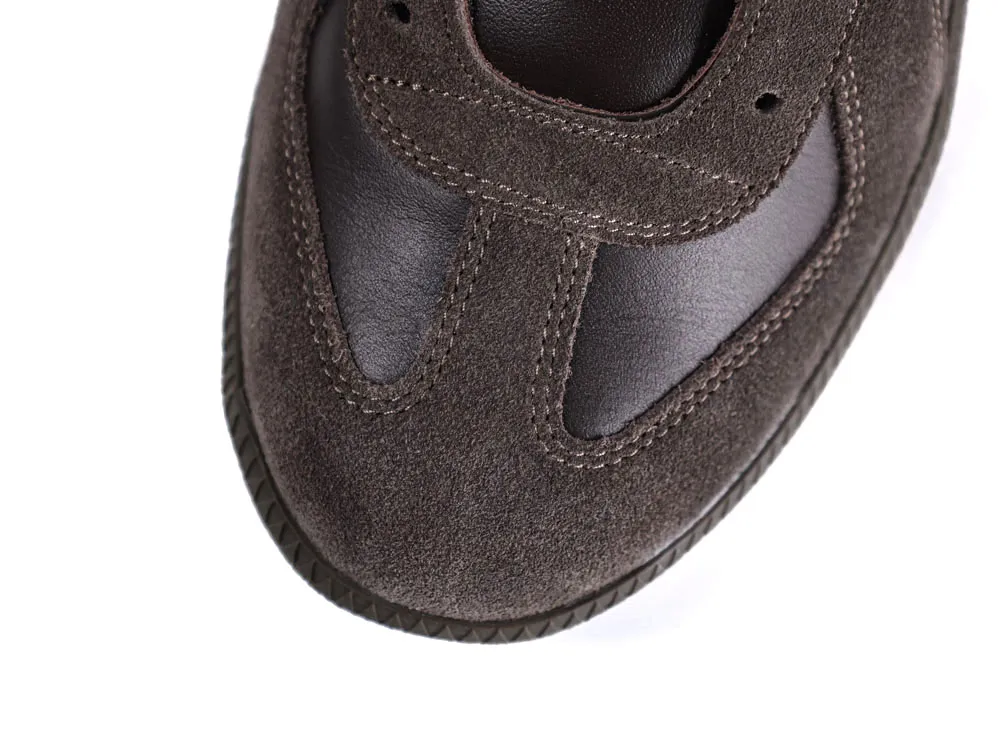 Close-up of a brown suede and leather sneaker upper, highlighting stitching details.
